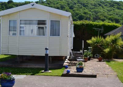 Mobile home with garden in scenic countryside setting.