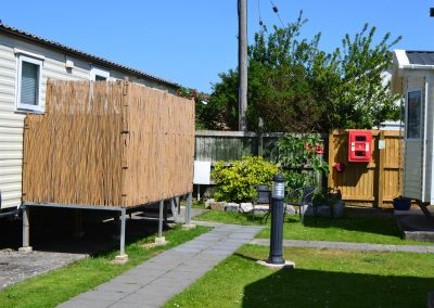 Caravan park with bamboo fencing and red postbox.