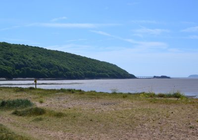 Coastal landscape with hill and pier, sunny day.